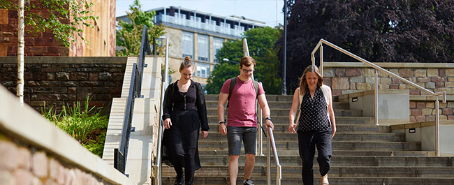 Three PG students walking down steps on campus.